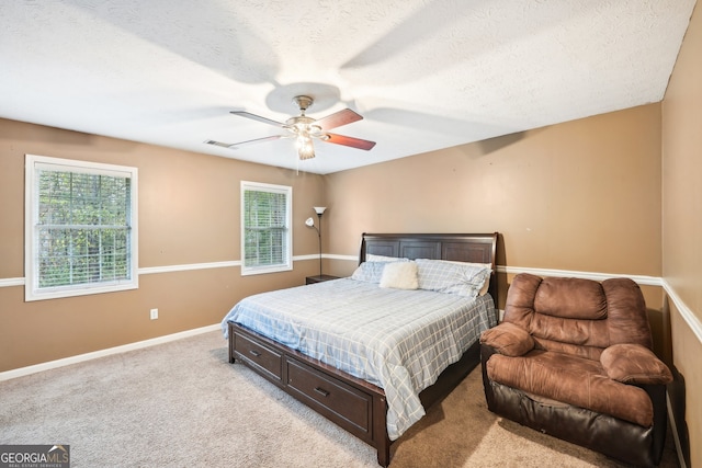 carpeted bedroom featuring ceiling fan and a textured ceiling