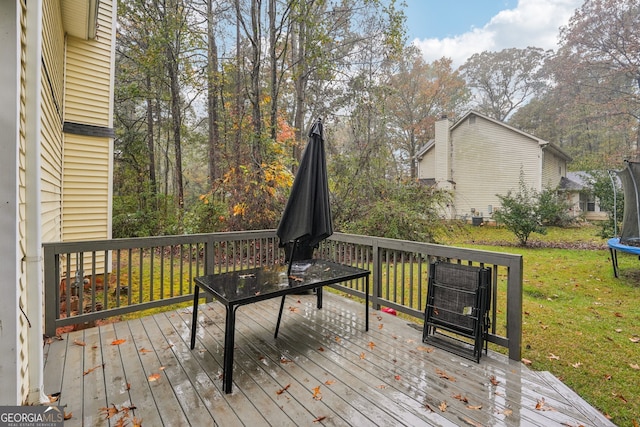 wooden deck with a trampoline and a lawn