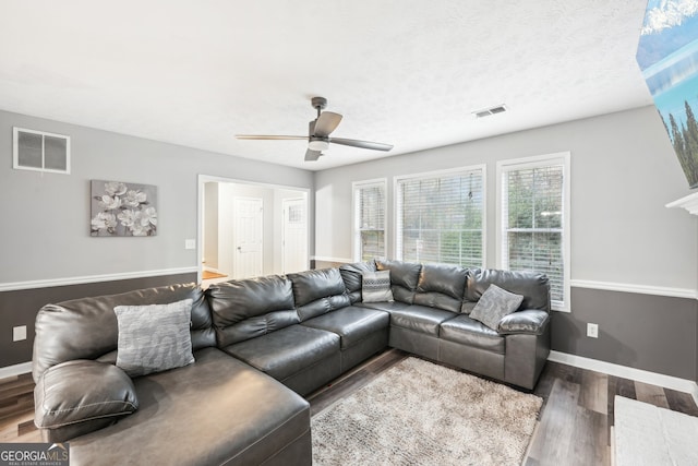 living room featuring ceiling fan, dark hardwood / wood-style flooring, and a textured ceiling