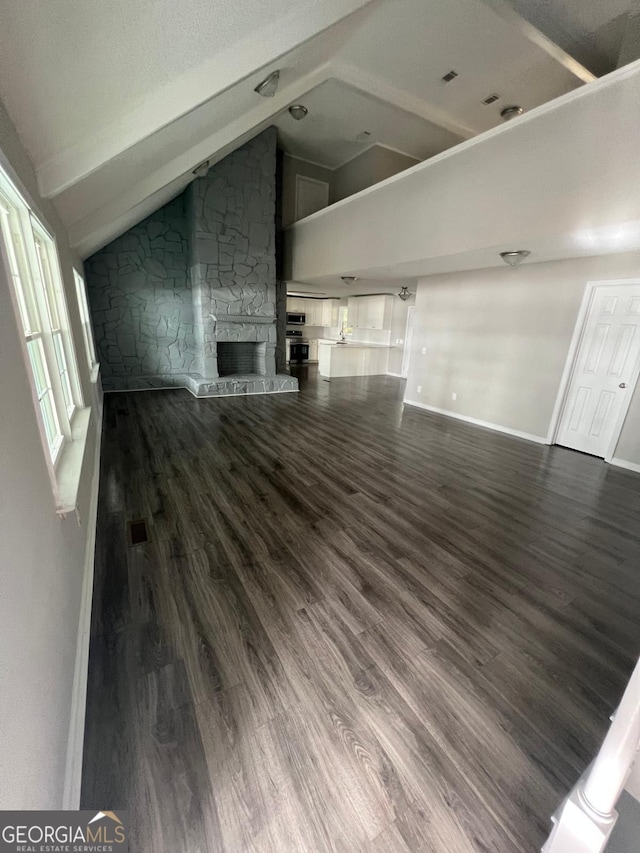 unfurnished living room featuring a fireplace, dark hardwood / wood-style flooring, and lofted ceiling