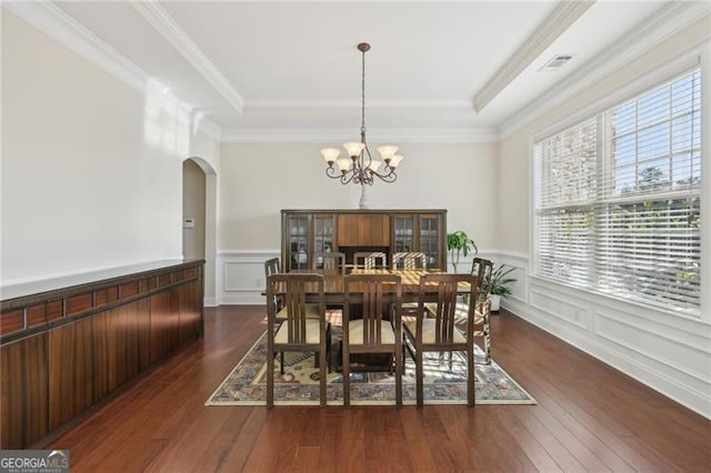 dining room featuring dark hardwood / wood-style flooring, ornamental molding, a tray ceiling, and a chandelier