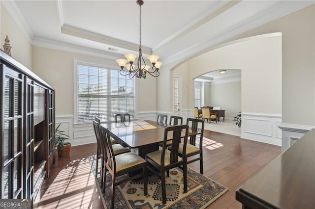 dining space with ornamental molding, an inviting chandelier, and dark wood-type flooring