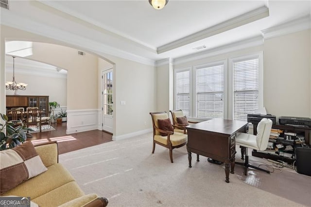 office space with a raised ceiling, ornamental molding, a notable chandelier, and hardwood / wood-style flooring