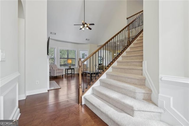 stairs featuring ceiling fan, a towering ceiling, and hardwood / wood-style flooring