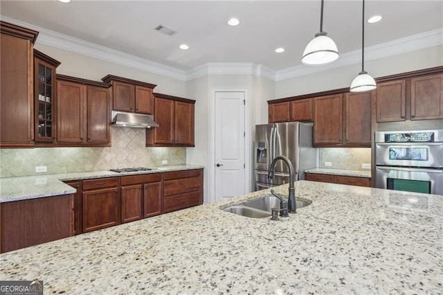 kitchen with pendant lighting, sink, light stone countertops, tasteful backsplash, and stainless steel appliances