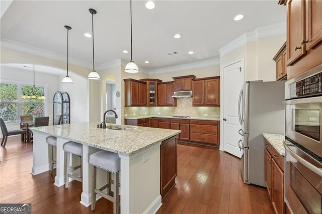 kitchen with sink, light stone counters, dark hardwood / wood-style floors, decorative light fixtures, and appliances with stainless steel finishes