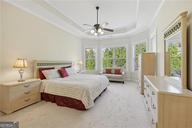 bedroom featuring ceiling fan, crown molding, light carpet, and a tray ceiling