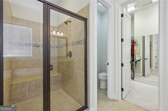 bathroom featuring tile patterned flooring, toilet, and an enclosed shower