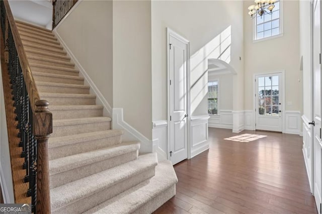 foyer entrance with a notable chandelier, dark wood-type flooring, and a high ceiling