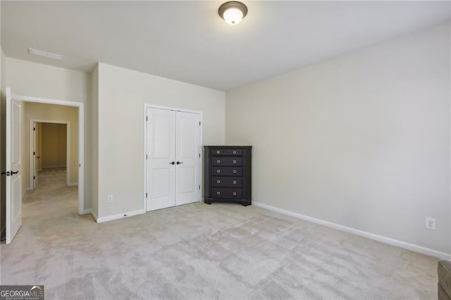 unfurnished bedroom with light carpet and a closet