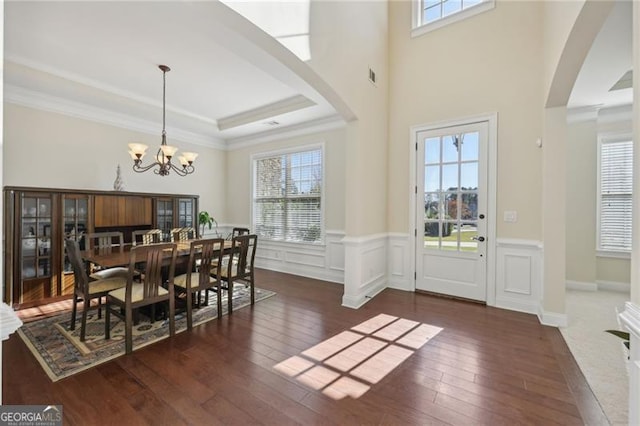 dining space featuring a raised ceiling, crown molding, dark wood-type flooring, and a chandelier