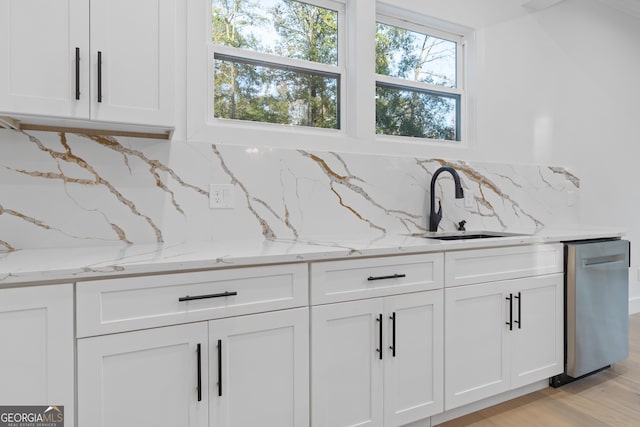 interior details with stainless steel dishwasher, decorative backsplash, sink, light stone countertops, and white cabinets