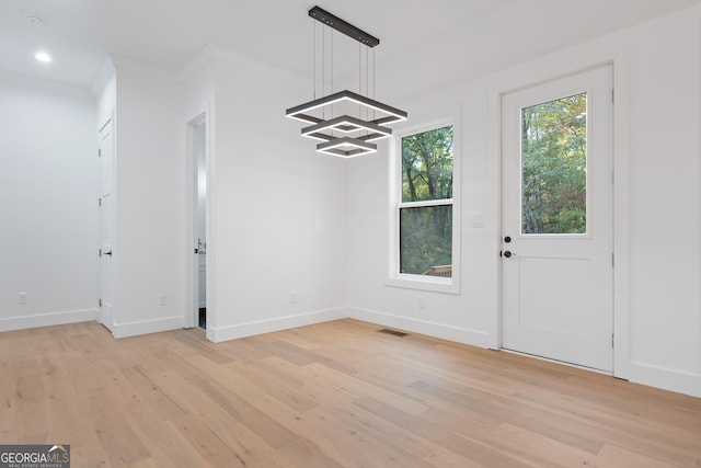 unfurnished dining area with ornamental molding and light hardwood / wood-style floors