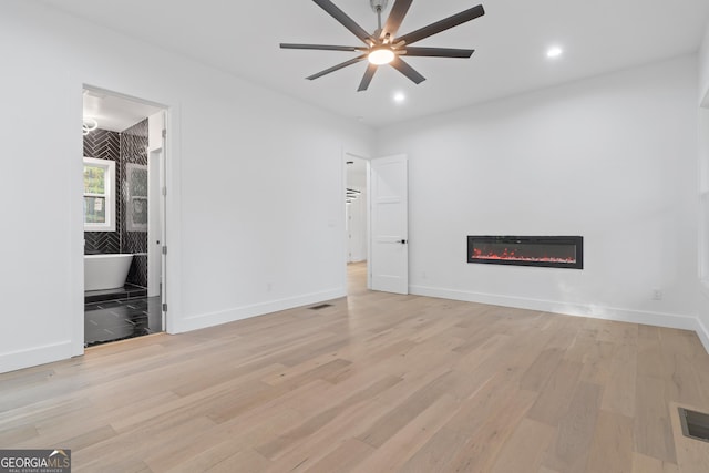 interior space featuring light hardwood / wood-style floors, ensuite bath, and ceiling fan