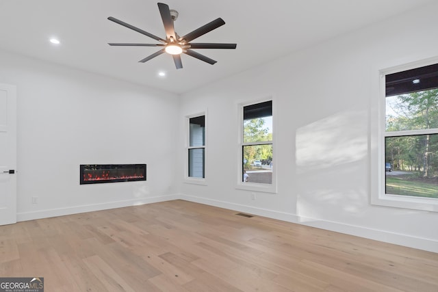 empty room featuring light wood-type flooring, ceiling fan, and a wealth of natural light