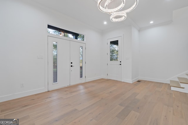 entrance foyer with crown molding, an inviting chandelier, and light hardwood / wood-style flooring