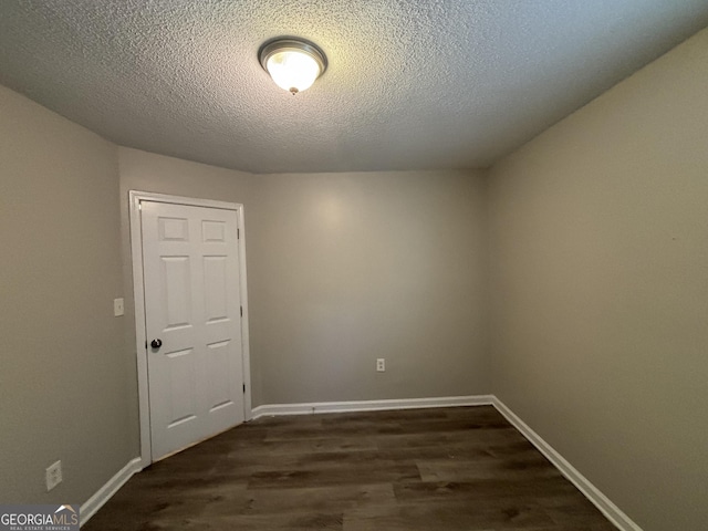 spare room featuring a textured ceiling and dark hardwood / wood-style floors