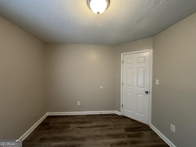 empty room with a textured ceiling and dark hardwood / wood-style floors