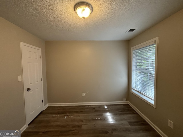 empty room with dark wood-type flooring and a textured ceiling