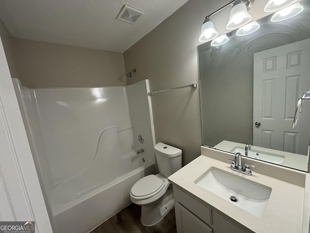 full bathroom with washtub / shower combination, toilet, wood-type flooring, vanity, and a textured ceiling