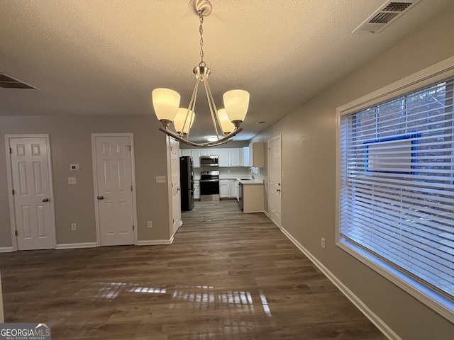 unfurnished dining area featuring sink, dark hardwood / wood-style floors, a textured ceiling, and a chandelier