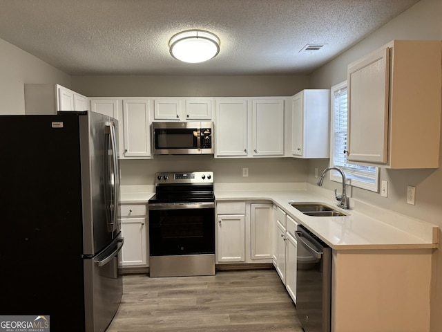 kitchen featuring sink, stainless steel appliances, white cabinetry, and wood-type flooring