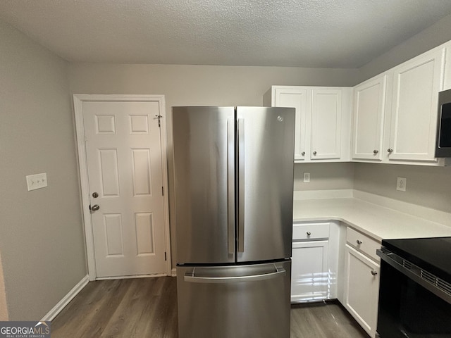 kitchen with electric range, a textured ceiling, stainless steel fridge, dark hardwood / wood-style flooring, and white cabinets