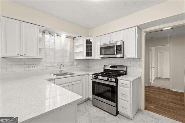 kitchen with sink, light stone countertops, appliances with stainless steel finishes, tasteful backsplash, and white cabinetry