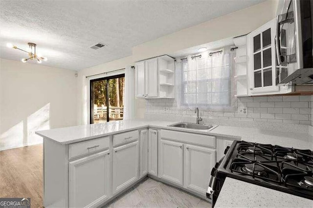 kitchen featuring kitchen peninsula, tasteful backsplash, stainless steel appliances, sink, and white cabinets