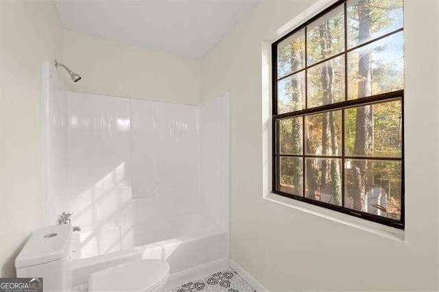 bathroom featuring tile patterned flooring, tiled shower / bath combo, a healthy amount of sunlight, and toilet