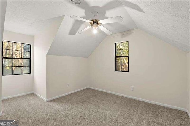 additional living space with a healthy amount of sunlight, a textured ceiling, and light carpet