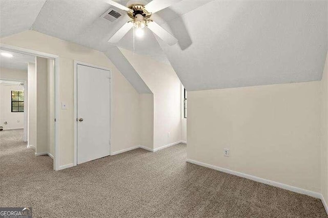 additional living space featuring a textured ceiling, light carpet, ceiling fan, and lofted ceiling