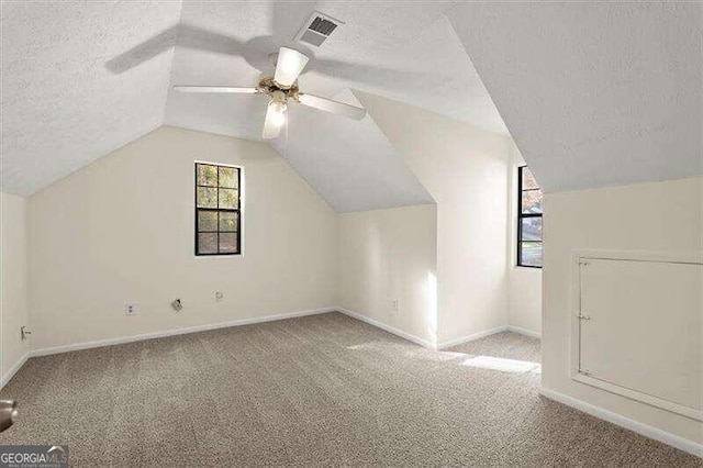 additional living space featuring lofted ceiling, ceiling fan, light carpet, and a textured ceiling