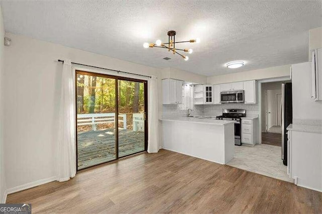 kitchen featuring white cabinets, a textured ceiling, stainless steel appliances, and light hardwood / wood-style floors