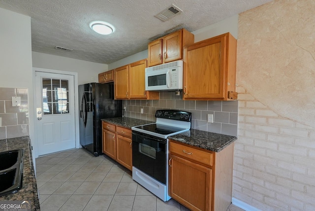 kitchen with backsplash, dark stone counters, a textured ceiling, white appliances, and light tile patterned floors