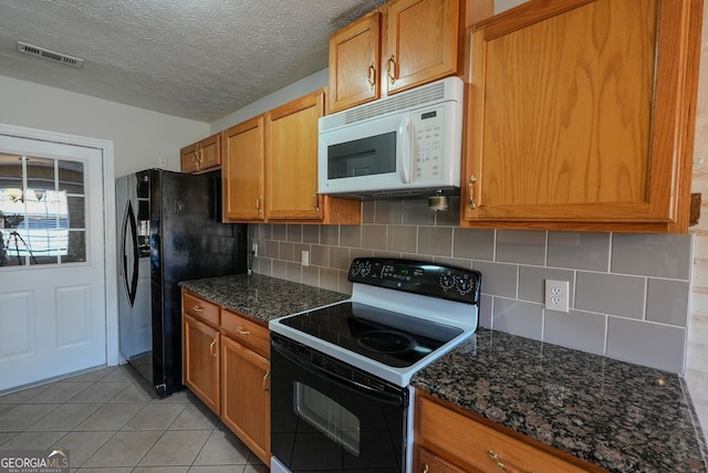 kitchen with a textured ceiling, white appliances, dark stone counters, and backsplash