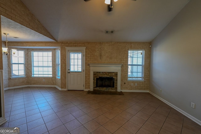 unfurnished living room with ceiling fan with notable chandelier, light tile patterned floors, a healthy amount of sunlight, and lofted ceiling