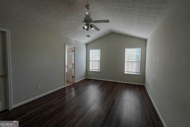 spare room with ceiling fan, dark hardwood / wood-style floors, a textured ceiling, and vaulted ceiling