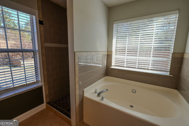 bathroom with tile patterned flooring, tile walls, and plus walk in shower