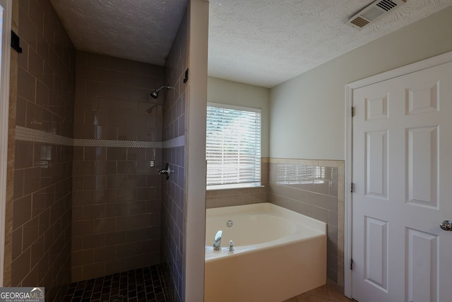 bathroom with tile patterned flooring, a textured ceiling, and separate shower and tub