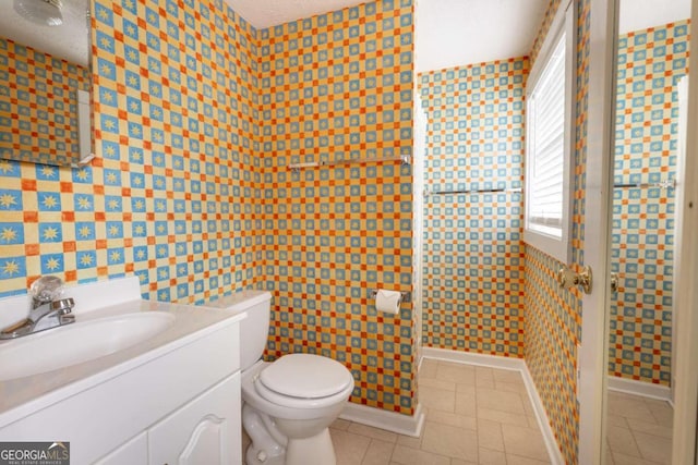 bathroom featuring tile patterned flooring, vanity, toilet, and a textured ceiling