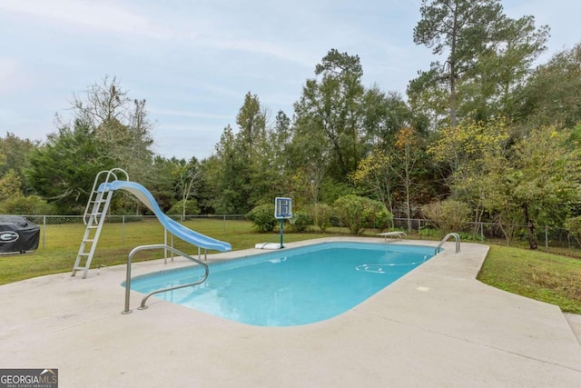 view of swimming pool featuring a lawn, a diving board, a patio, and a water slide