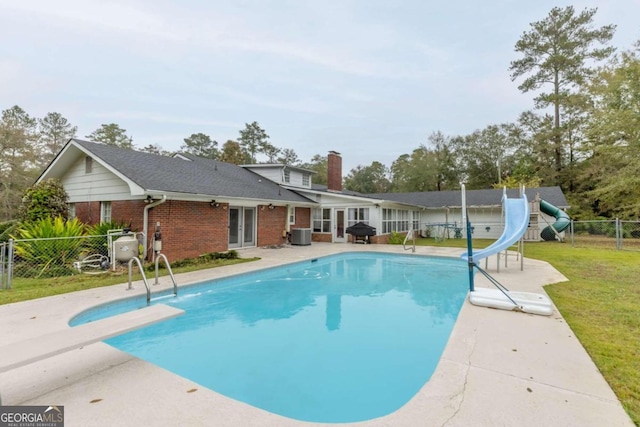 view of pool with a lawn, a diving board, a water slide, area for grilling, and a patio