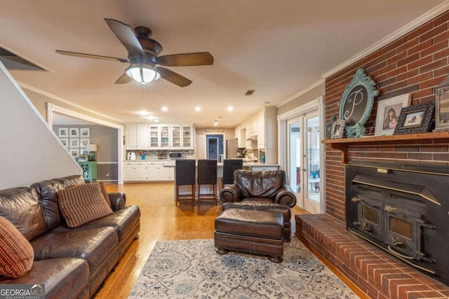 living room featuring crown molding, light hardwood / wood-style flooring, ceiling fan, and french doors