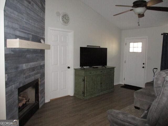 living room featuring lofted ceiling, a fireplace, dark wood-type flooring, and ceiling fan