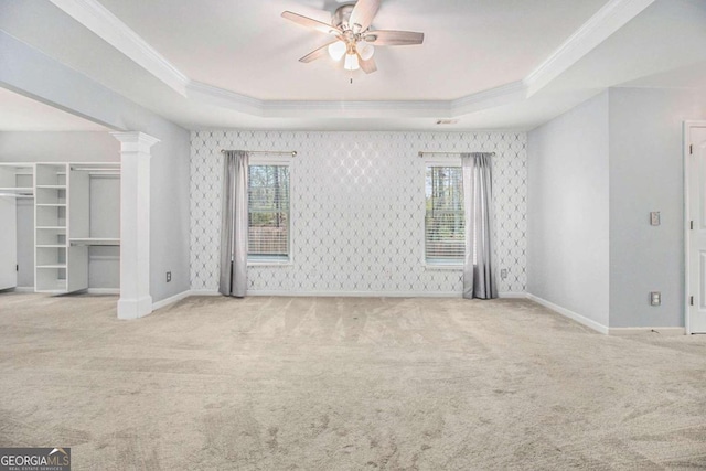 carpeted empty room with a raised ceiling, a wealth of natural light, and ceiling fan