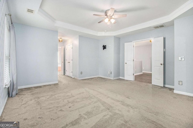 unfurnished bedroom featuring a raised ceiling, ceiling fan, light colored carpet, and ornamental molding