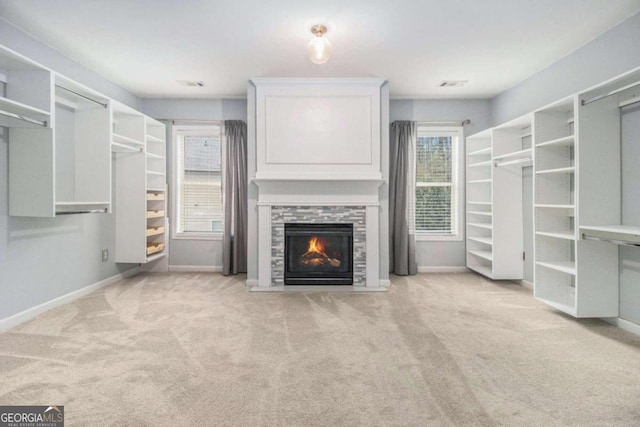 spacious closet with light carpet and a tile fireplace