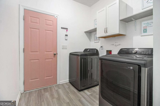 laundry room with cabinets, washing machine and dryer, and light hardwood / wood-style floors