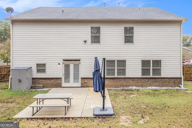 rear view of property with a lawn, a patio area, and a shed